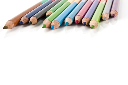 Color pencils in arrange in color wheel colors on white background with copy space