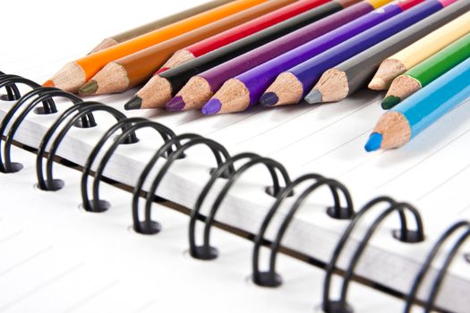 Color pencils in arrange in color wheel colors on note book with copy space