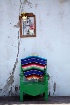 picture of an old and decorative mexican patio with a chair and some flowers