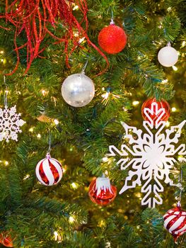 Red and White Christmas Ornaments on a Green Tree with White Lights