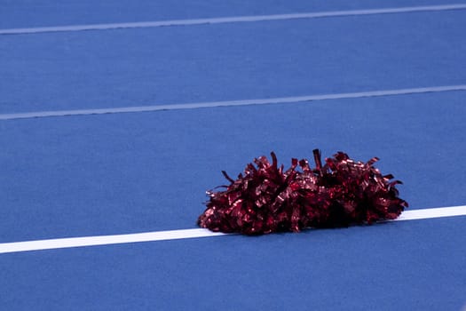 Cheerleading compitition pom poms on a blue mat with lines.