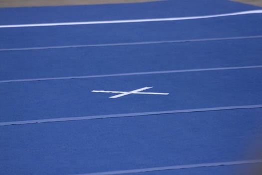 Cheerleading compitition pom poms on a blue mat with lines.