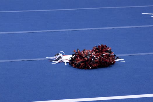 Cheerleading compitition pom poms on a blue mat with lines.