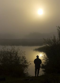 Morning on the foggy river. The person fishes. The river in Belarus