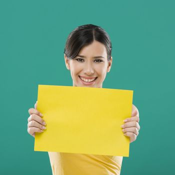 Beautiful asian woman holding a yellow billboard, over a green background