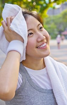 Asian woman wiping sweat with a towel after exercising
