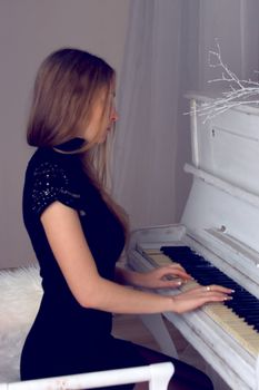 girl with blond long  hair in  dress playing white piano