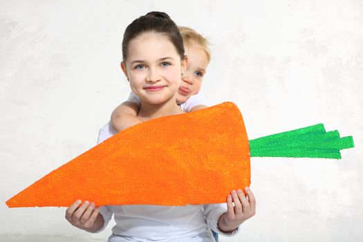Brother and sister posing with painted carrot in studio