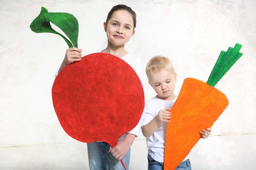 Brother and sister posing with painted carrot and beet