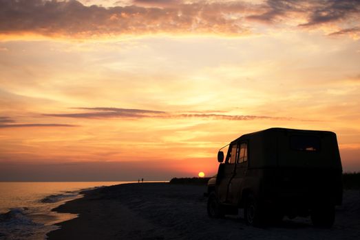 people on the beach at sunset time, parked car