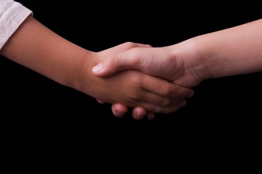 Two children shaking hands, cuacasian an hispanic on black