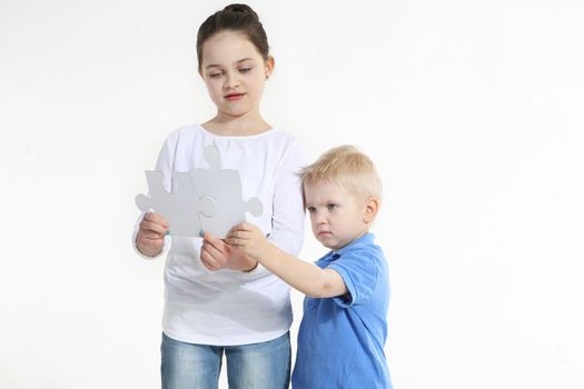 Sister and brother play with puzzle pieces isolated on white