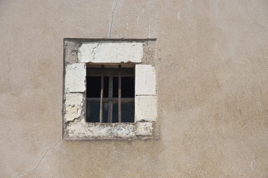 A wall with a small window with bars