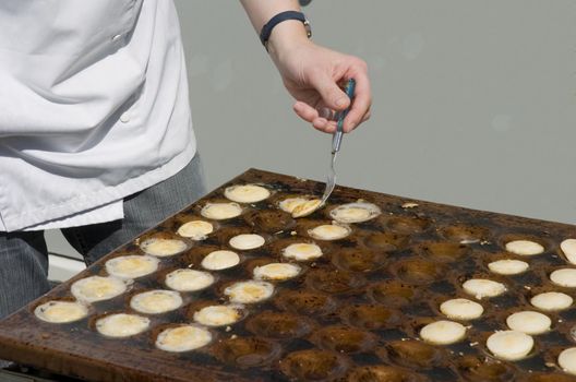 Person baking small Dutch pancakes