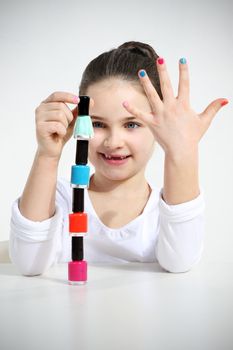 Little girl builds a pyramid using nail polishes
