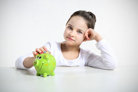 Portrait of little girl with piggy bank isolated on white