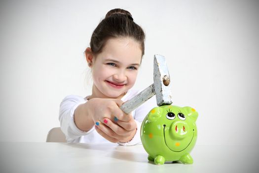 Little girl breaking piggy bank isolated on white