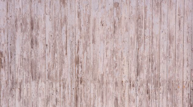 Wooden garage wall with flaked paint and rusty nails