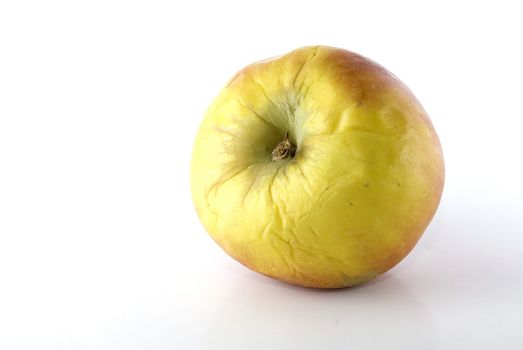 Wrinkled apple on white surface