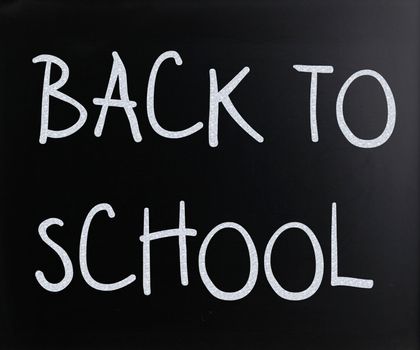 "Back to school" handwritten with white chalk on a blackboard