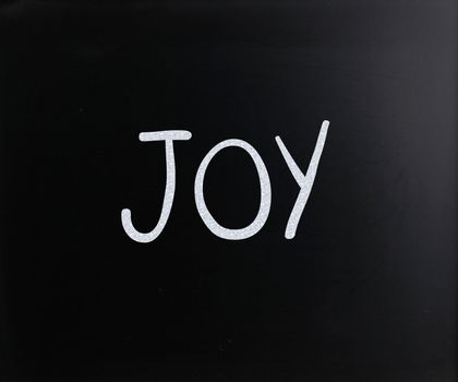 The word "Joy" handwritten with white chalk on a blackboard