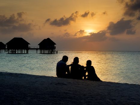 Silhouette of family on vacation having a drink at sunset