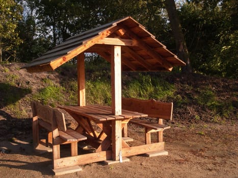 Wooden picnic table with shade roof outdoors in nature