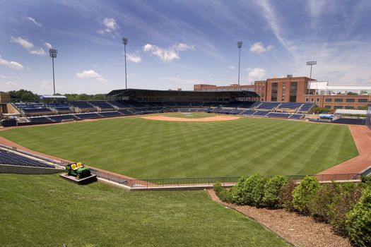 Public ballpark just after grass was mowed with a blue sky