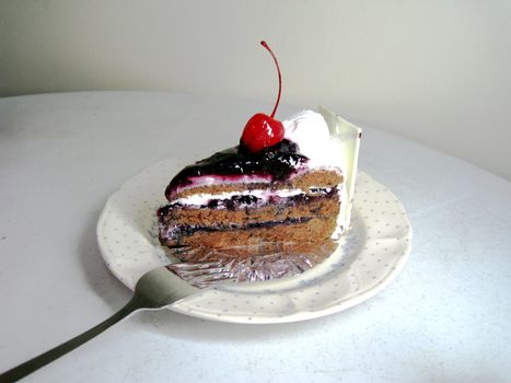 a slide of black forest cake with cherry on top and white chocolate