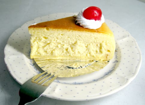 a slide of lemon cheese cake with cherry on top