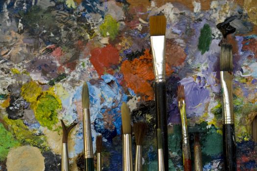 Paintbrushes used and dirty color. Palette on the background