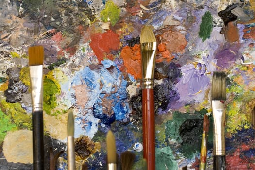 Paintbrushes used and dirty color. Palette on the background