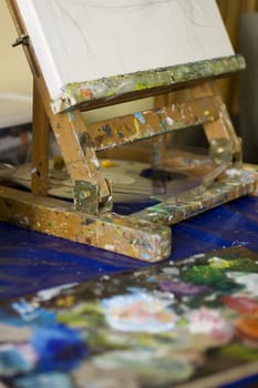 Atelier. Palette with colors, easel in the background