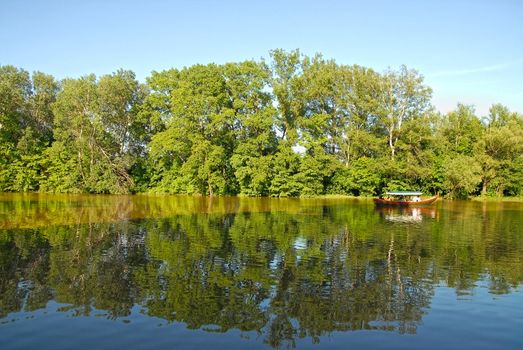 Touristic boat on the lake. Summer time. Royal park in Wilanow near Warsaw.