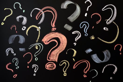 Questions, decision making or uncertainty concept - a pile of colorful question marks drawn on a blackboard
