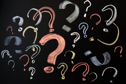 Questions, decision making or uncertainty concept - a pile of colorful question marks drawn on a blackboard