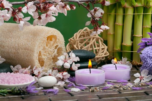 Spa concept with aromatic candles, cotton towels, loofah, bath salt and healing pebbles