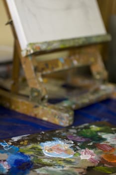 Atelier. Palette with colors, easel in the background