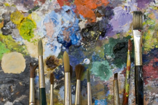 Paintbrushes used and dirty color. Palette on the background