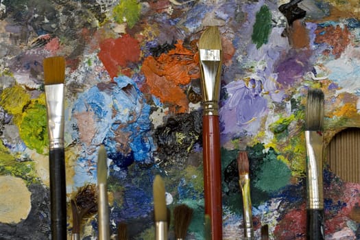 Paintbrushes used and dirty color. Palette on the background