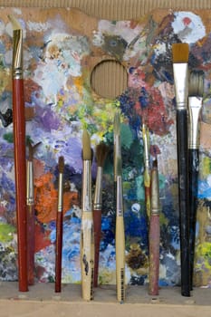 Paintbrushes used and dirty color. Palette on the background