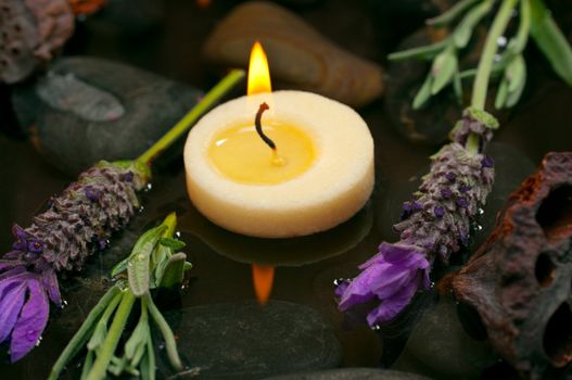 Spa concept with aromatic candles, lavender, healing pebbles and water