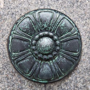 Close-up of decorative metal piece on granite wall.