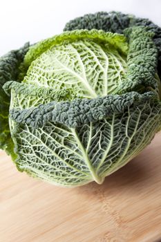 Head of green leaf cabbage on cutting board.