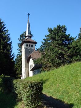 Bell-tower of a small white church surrounded by trees by beautiful weather