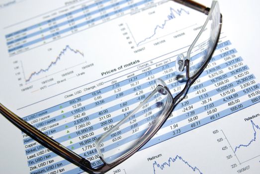 Glasses on printed stock report with graphs and tables.