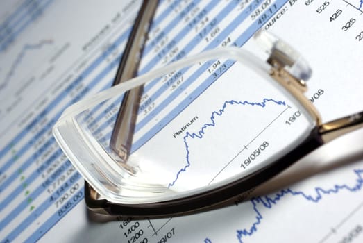 Glasses and printed financial report with data, charts.