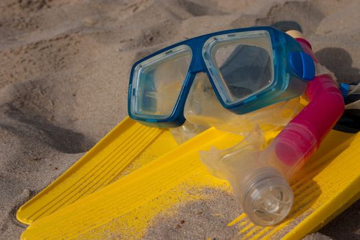 Yellow flippers with snorkel goggle and tube on the beach