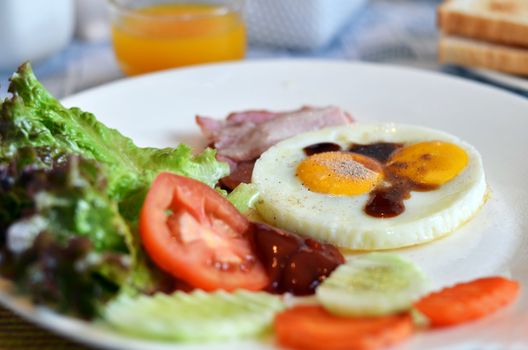 american style breakfast , with bacon, fried egg and fresh vegetables