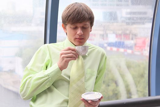 The businessman drinks coffee at office from a small white cup